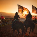 Riders carrying american flags at rodeo